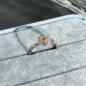 Detailed macro view of a silver flower ring with red stone in a blue velvet box