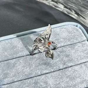 Close-up of an elegant silver floral open ring featuring a pomegranate red stone