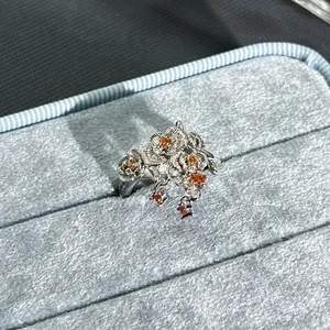 Macro detail of an elegant silver flower ring featuring pomegranate red gemstones