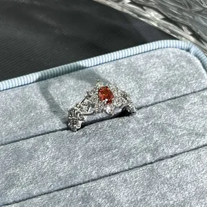 Detailed close-up of a silver flower ring with a garnet red oval center stone