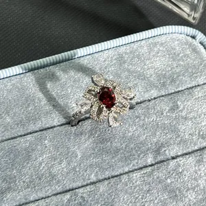 Close-up of elegant flower ring with oval garnet red gemstone in blue box
