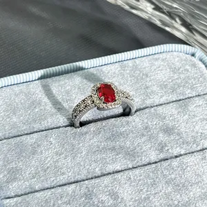Close-up of elegant garnet red halo ring with sparkling accent stones in light blue box