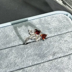 Detailed close-up view of an elegant silver flower open ring with red heart stones
