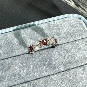 Macro detail view of a silver-tone ring set with red and clear stones on blue velvet.