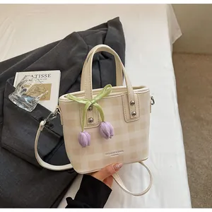 Détail du sac seau à carreaux crème avec de jolis charms en forme de tulipe mauve