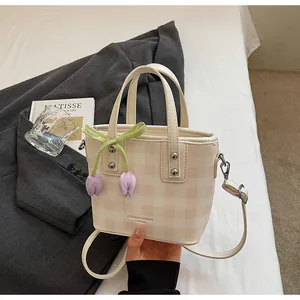 Gros plan d'un sac seau à carreaux crème élégant avec un joli détail de tulipe.