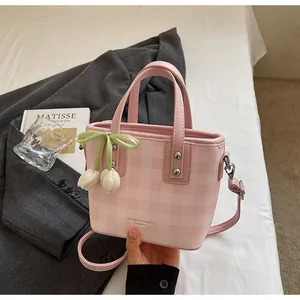 Détail d'un sac seau à carreaux roses avec charm tulipe blanche et nœud vert