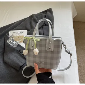 Sac seau à carreaux gris élégant doté d'un nœud vert et de jolies breloques florales.
