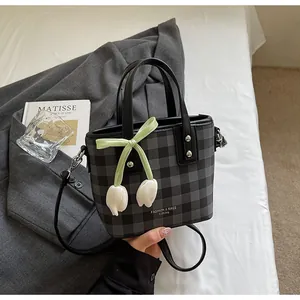 Vue détaillée du sac seau à carreaux gris élégant avec un joli pendentif tulipe