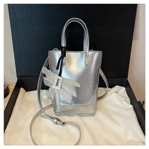 Detailed view of silver metallic mini bucket bag with fabric flower charm in gift box