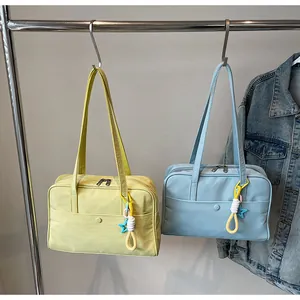 Vue détaillée de grands sacs fourre-tout en nylon jaunes et bleus suspendus à un support.