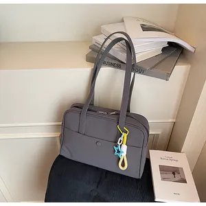 Vue détaillée d'un sac à bandoulière gris minimaliste avec un pendentif étoile coloré