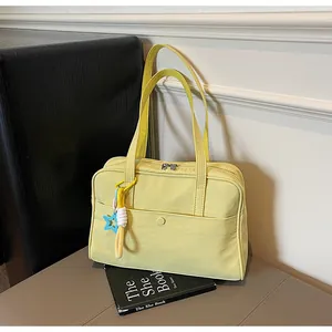 Vue détaillée d'un sac cabas en nylon jaune clair avec un charm étoile décoratif sur la bandoulière.