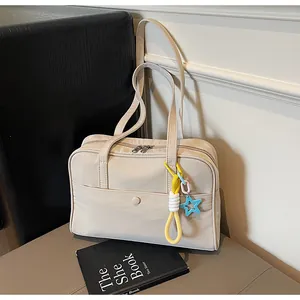 Gros plan d'un sac à bandoulière crème minimaliste avec un détail de breloque étoile coloré