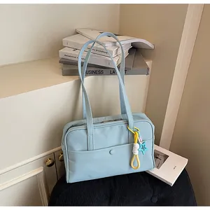 Détail d'un sac cabas d'étudiant bleu clair avec un porte-clés étoile coloré sur la bandoulière.