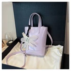Close-up of light purple handbag with floral charm in a black gift box