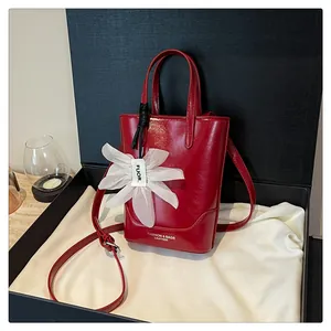 Chic red mini bucket bag with white flower charm displayed in a premium black gift box