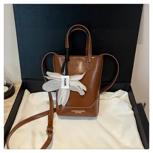 Stylish brown glossy leather bucket bag for women with decorative white flower charm