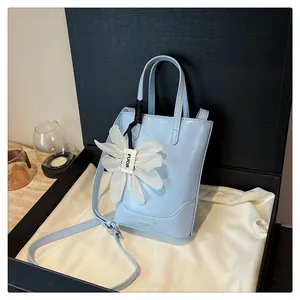Detailed view of sky blue mini bucket bag with elegant white flower charm