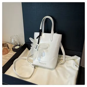 Elegant white leather bucket bag with flower charm and shoulder strap in gift box