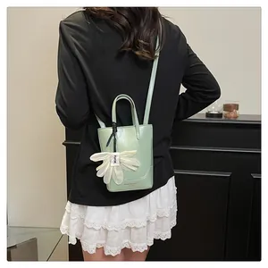 Back view detail of a stylish green leather bucket bag with a delicate flower charm