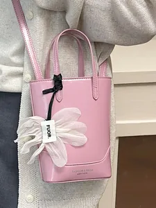 Chic pink leather bucket bag with flower charm, crossbody or hand-carry style.