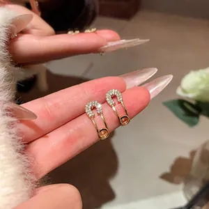 Close-up view of elegant gold-plated safety pin earrings with micro-set rhinestones