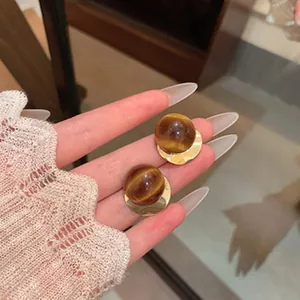 Macro view of French vintage earrings featuring tiger eye spheres and golden bases