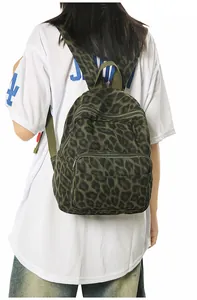 Detail view of a stylish dark green leopard print canvas backpack worn by a female model.