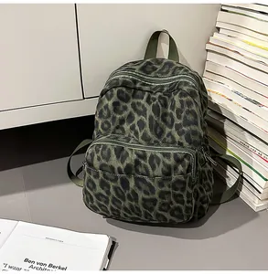 Stylish leopard print canvas backpack next to a stack of books in a minimalist setting