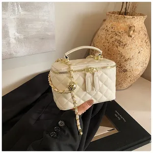 Elegante bolso acolchado crema con cadena dorada sobre fondo de chaqueta negra