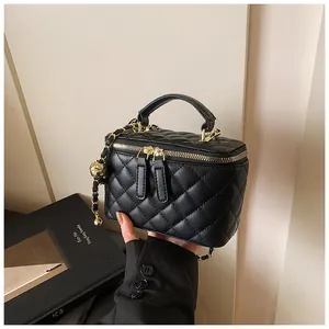 Primer plano de mini bolso negro acolchado con cadena dorada y colgante