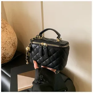 Primer plano de mini bolso acolchado negro con cadena dorada y asa superior.