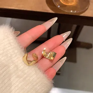 Macro detail of elegant gold micro-inlaid pin-shaped earrings held against a soft sweater.