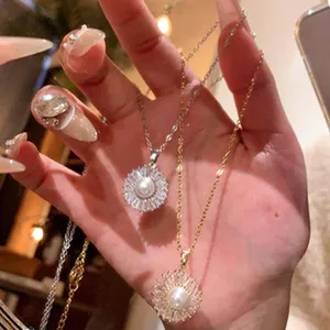 Primer plano de collares de sol en plata y oro con perla centrale y cristales brillantes.