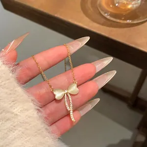 Primer plano de un collar con colgante de lazo dorado con piedras lunares y diamantes de imitación