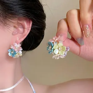 Close-up of elegant floral cluster earrings featuring pastel petals and bead accents