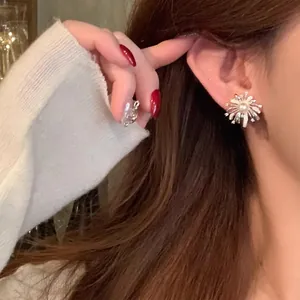 Close-up of silver firework stud earrings with a pearl center on ear.