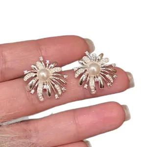 Elegant silver-tone fireworks stud earrings with pearl center and cubic zirconia stones.