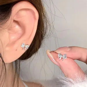 Close-up of sparkling silver bow stud earrings showing worn effect and texture