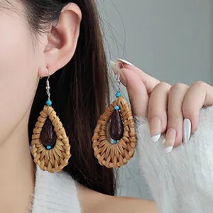 Close-up detail of bohemian woven rattan drop earrings with turquoise beads on a model