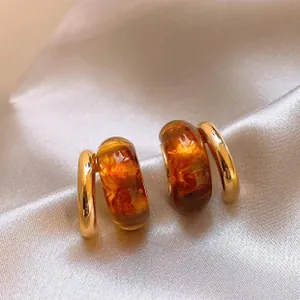 Macro detail view of amber translucent resin earrings with polished gold hoop details