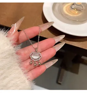 Primer plano del elegante collar de candado Ruyi con piedra lunar, diamantes y campanas.