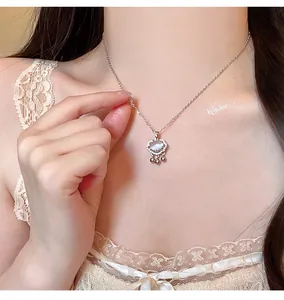 Detalle elegante de collar de candado de paz en plata con piedra lunar y campanas