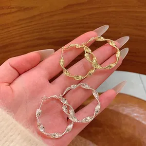 Detailed view of large vintage twisted hoop earrings in gold and silver metal finishes