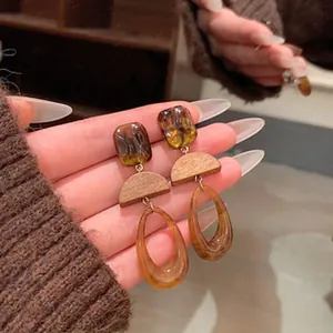 Detailed view of vintage Maillard amber resin and wood hollow oval dangle earrings