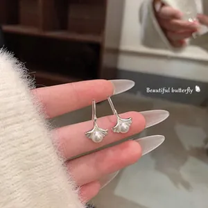 Detailed close-up of vintage silver ginkgo leaf drop earrings featuring a central pearl accent