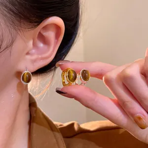 Detail view of vintage oval tiger eye stone stud earrings in gold and silver finish
