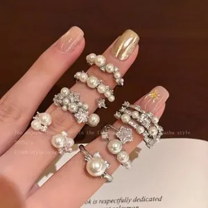 Detailed view of elegant pearl and star-themed rings with silver finish on fingers