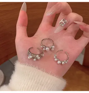 Detailed view of three elegant silver-toned pearl rings displayed in a person's hand